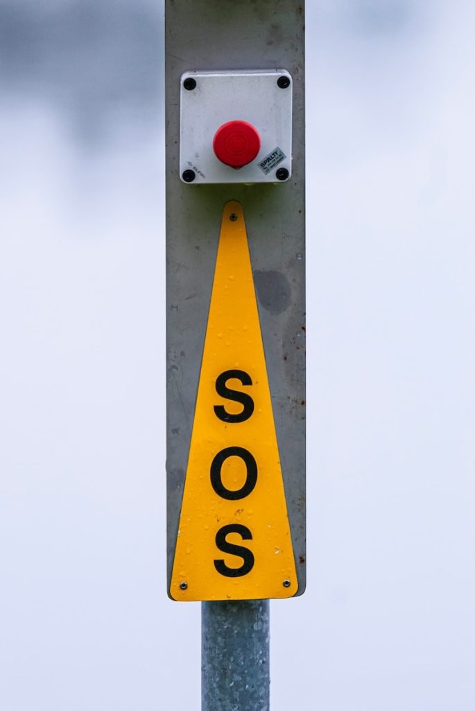 yellow and black SOS sign with red stop push button